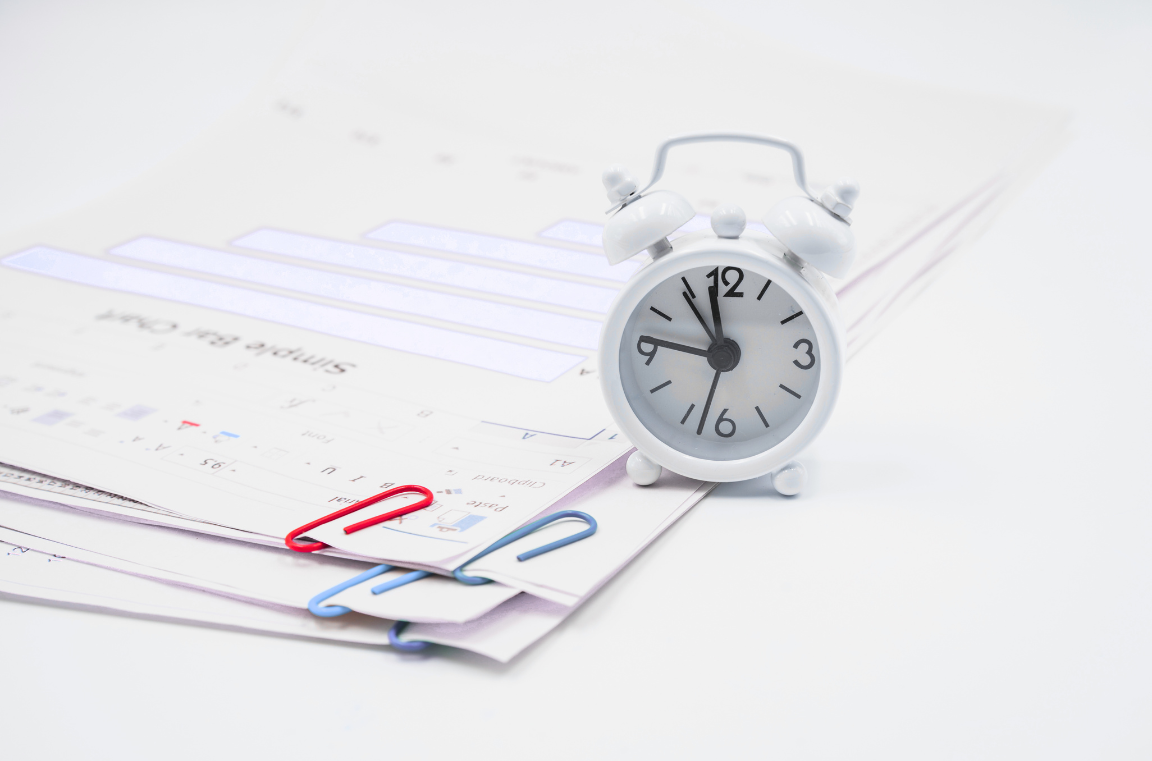 Relógio e documentos com clipes de papel representam a importância do timing e da organização na criação de um plano de marketing.